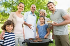 Portrait of an extended family standing at barbecuing in the park